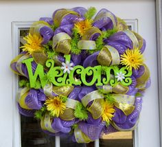 a purple and yellow wreath with the word welcome hanging on it's front door