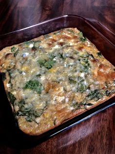 a square casserole dish with spinach and cheese on it sitting on a wooden table