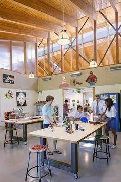 a group of people standing around a table in a room with wooden beams on the ceiling