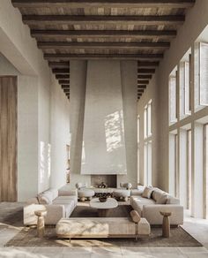 a large living room with white couches and wooden beams on the ceiling is shown