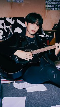 a young man sitting on top of a couch holding an acoustic guitar in his hand