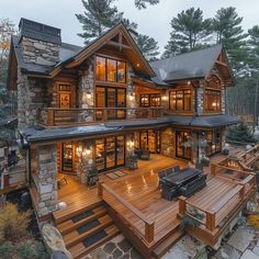 a large wooden house with lots of windows and lights on it's sides, in the woods