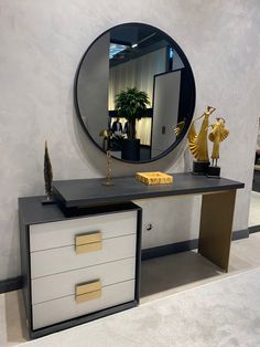 a black and white dresser with a mirror on it's wall next to a plant