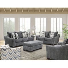 a living room filled with gray furniture and lots of pillows on top of it's couches