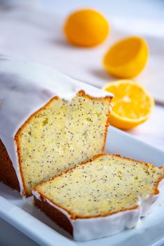 a loaf of lemon poppy seed bread on a plate with oranges in the background