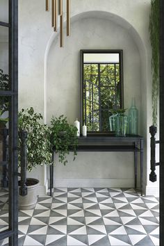 an entryway with black and white tiled flooring, potted plants and mirrors