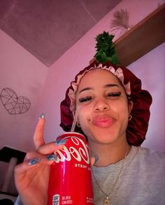 a woman holding a red can with a frisbee on top of her head