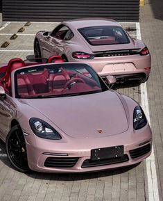 two pink sports cars parked next to each other