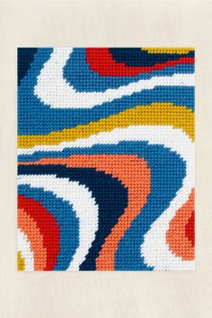 a cross - stitch pattern in blue, red, yellow and white with an abstract design