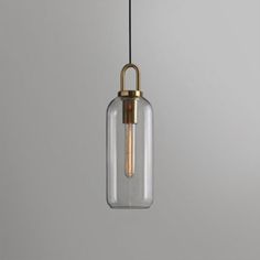 a glass and brass pendant light hanging from a ceiling