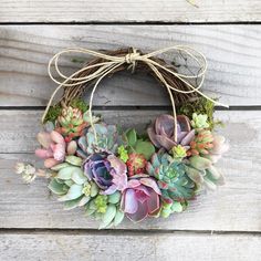 a wreath with succulents is hung on a wooden wall, ready to be used as a decoration