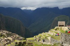 people are standing at the top of a mountain looking down on some ruins and mountains