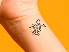 a small tattoo on the wrist of a person with a turtle in it's shell