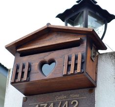 a wooden clock on the side of a building with a heart carved into it's face