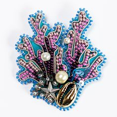 a brooch with beads and pearls in it on a white surface, next to a starfish