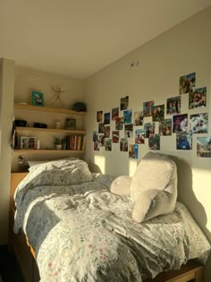 an unmade bed in a bedroom with pictures on the wall and shelves above it