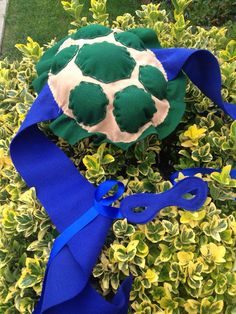 a stuffed turtle sitting on top of a bush with blue ribbon around it's neck