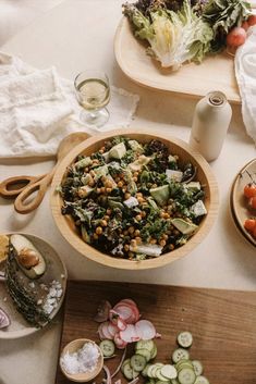 a table topped with plates and bowls filled with food next to utensils on top of a wooden cutting board