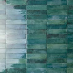 a tile wall with green and blue tiles on the bottom, in an abstract pattern