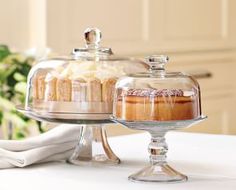 two cakes sitting on top of a cake stand under a glass dome covered in frosting