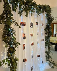 the curtain is decorated with photos and lights in front of a mirror that has greenery growing on it