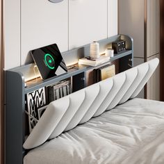 there is a bed with many books and electronics on the headboard in this room