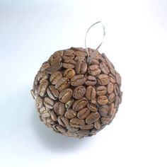 a ball of coffee beans on a white surface with a hook in the middle that is hanging from it's side