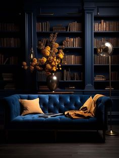 a blue couch in front of a bookshelf filled with lots of books and flowers