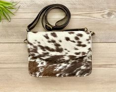 This gorgeous bag is crafted in 100% GENUINE COWHIDE FUR and NATURAL COW PRINT ON BOTH SIDES. The bag features REAL CALF LEATHER BACK, TASSEL and ADJUSTABLE crossbody STRAP. Inside is CLOTH LINED with 1 OPEN POCKET and 1 ZIP POCKET. The strap is detachable to covert into a clutch or make up bag to be tossed into a larger bag Size: 8.75 Inches x 6.5 Inches Light weight design; can be comfortably carried all day Durable real cowhide- low maintenance Easy to clean Cow Hide Purses, Cowhide Purse, Cowgirl Accessories, Cowgirl Gifts, Brown Cow, Brown Cowhide, Fur Bag, Cow Girl, Cow Hide