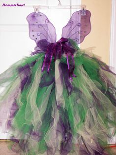 a green and purple tutule dress hanging in front of a door with the words, halloween written on it