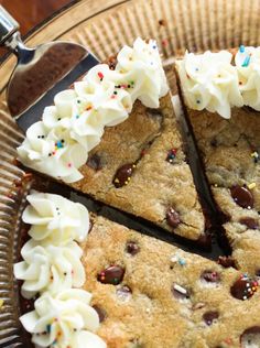 a chocolate chip cookie cake with white frosting and sprinkles