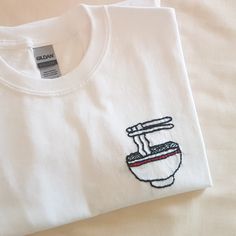 a white t - shirt with a bowl and chopsticks embroidered on it