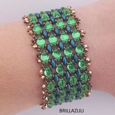 a close up of a person's arm wearing a bracelet with green and blue beads