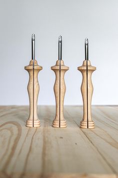 three wooden candlesticks are lined up on a table