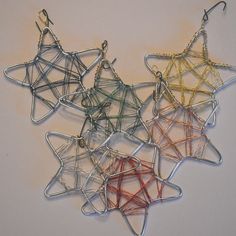 five star shaped wire hangers on a white surface, each with different colors and sizes