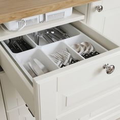 an open drawer in a kitchen with utensils and other items inside the drawers