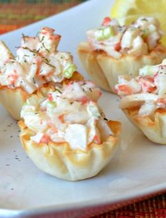 small appetizers on a plate with lemon wedges