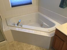 a bathroom with a large bathtub next to a sink and shower head mounted on the wall