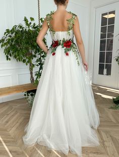 a woman in a white wedding dress with red flowers on it's waist and back