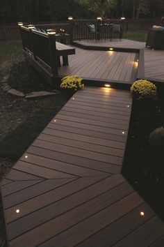 a deck with lights on it and some flowers in the grass next to it at night