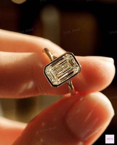 a close up of a person holding a ring with a diamond in it's middle