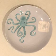 an octopus on a white plate with blue swirls and a tag attached to it