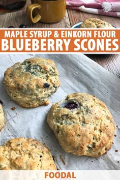 four blueberry scones on a baking sheet with text overlay that reads maple syrup & enikoon flour blueberry scones