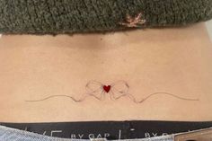 a woman's stomach with a small red heart on her lower back and the word love spelled in cursive writing