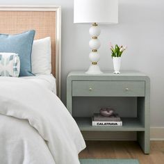 a bedroom with a bed, nightstand and flowers on the night stand next to it