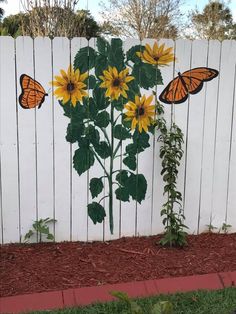 a white picket fence with sunflowers and butterflies painted on it