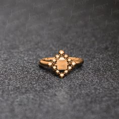 a gold ring with beads on it sitting on a black surface, in front of a gray background