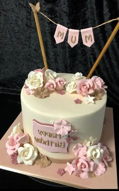 a birthday cake decorated with pink and white flowers