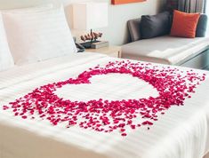 a bed with white sheets and red petals on it