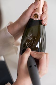 a person holding a wine bottle with writing on it and an object in the other hand